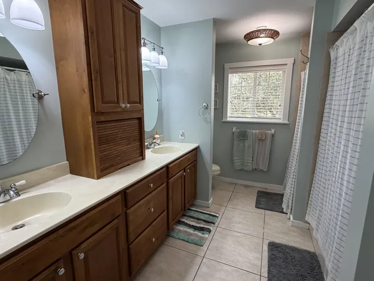 The master bathroom with a double vanity, separate shower and a window to the trees
