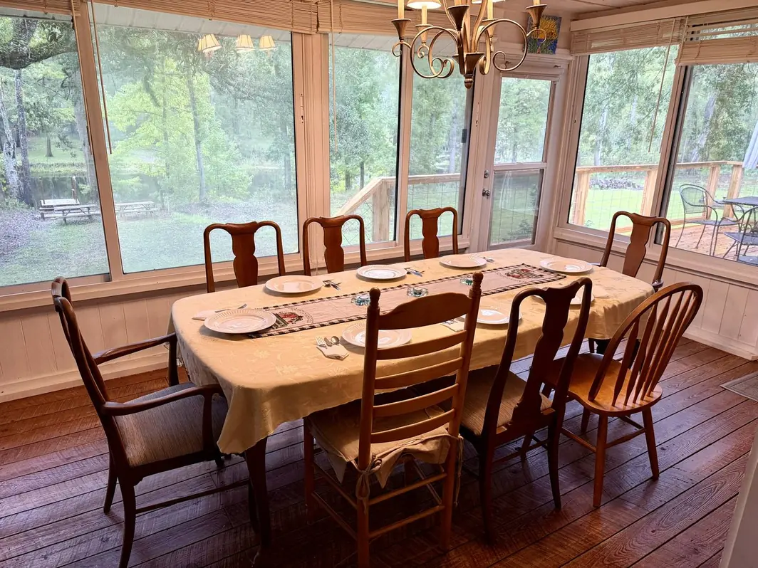 The Florida room dining table beneath walls of windows overlooking the river