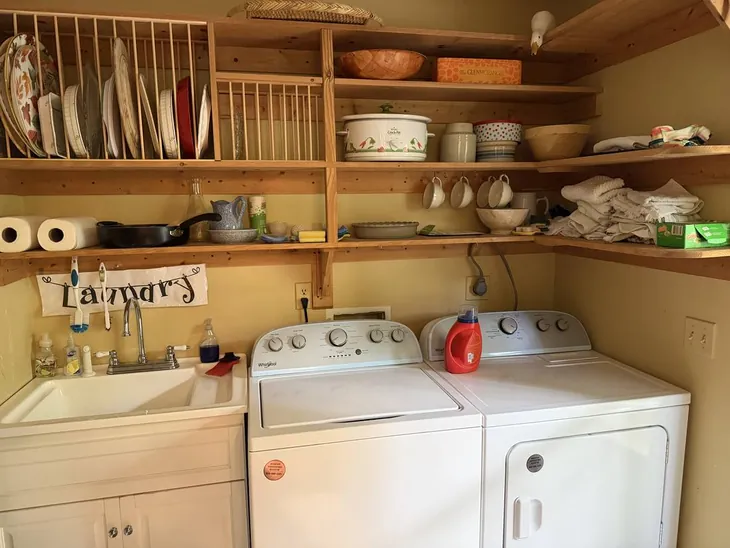 The laundry room with washer, dryer, deep sink and open shelving